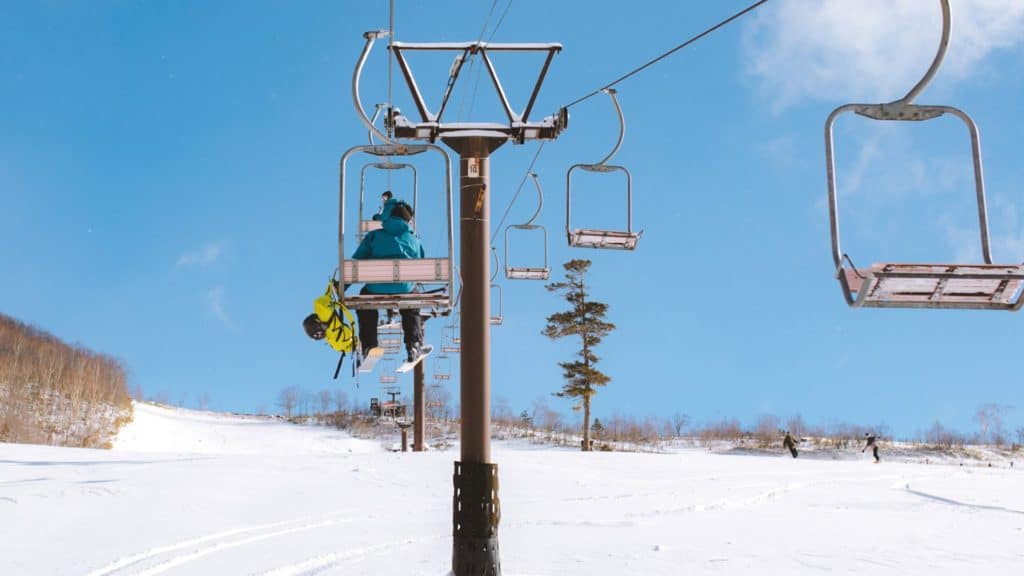 People riding the Tsugaike ski lifts on a bluebird day